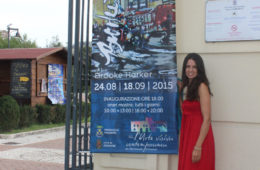 artist Brooke Harker with exhibition banner in Italy